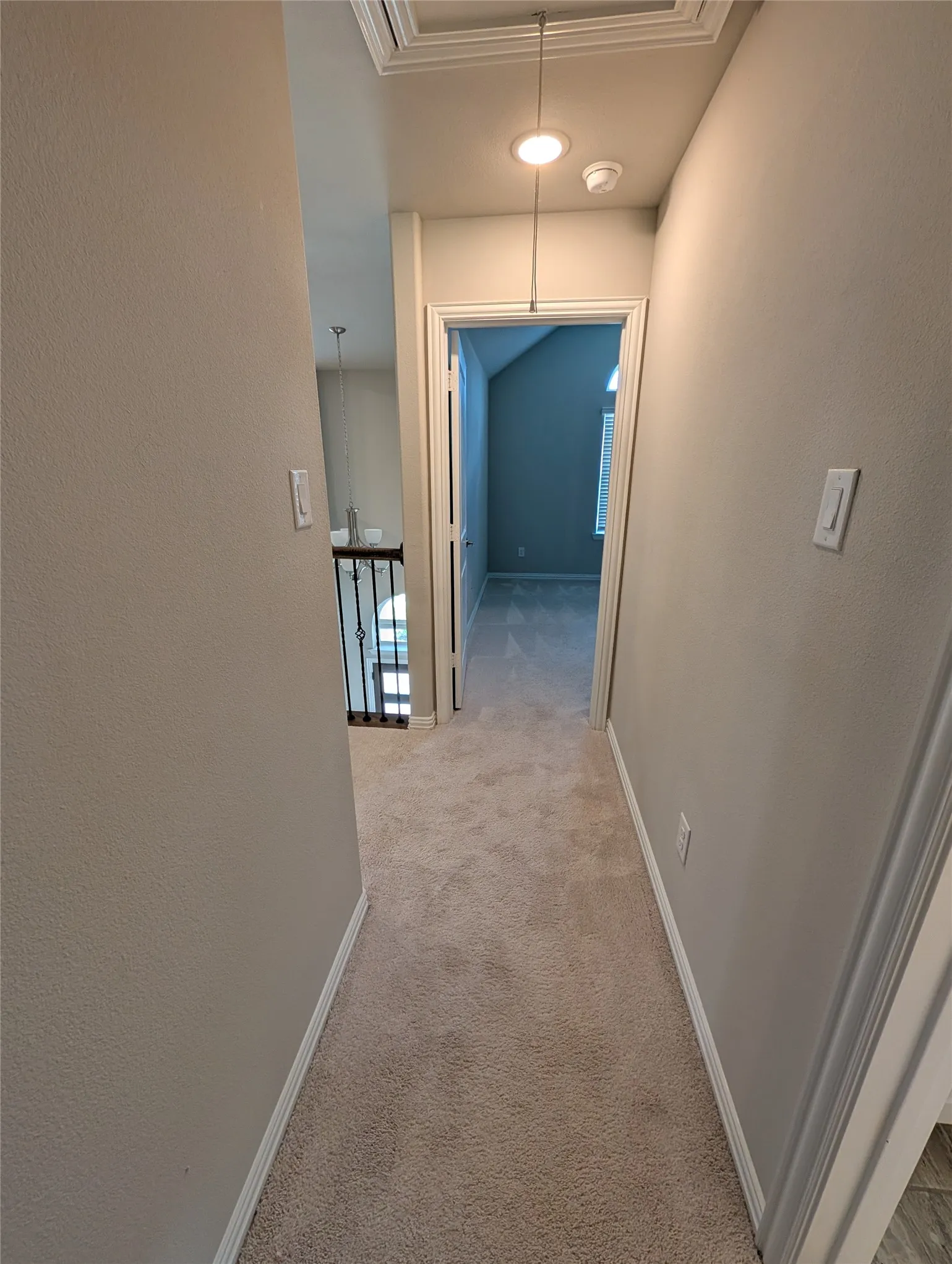 Carpeted hallway featuring overhead recessed lighting, attic access panel, and a black wrought iron railing