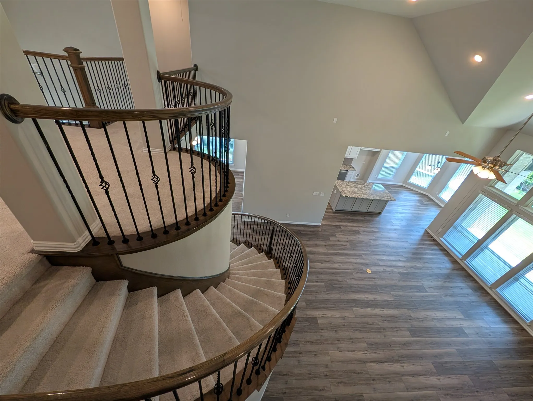 Curved staircase with wood-finish handrails and decorative wrought iron balusters