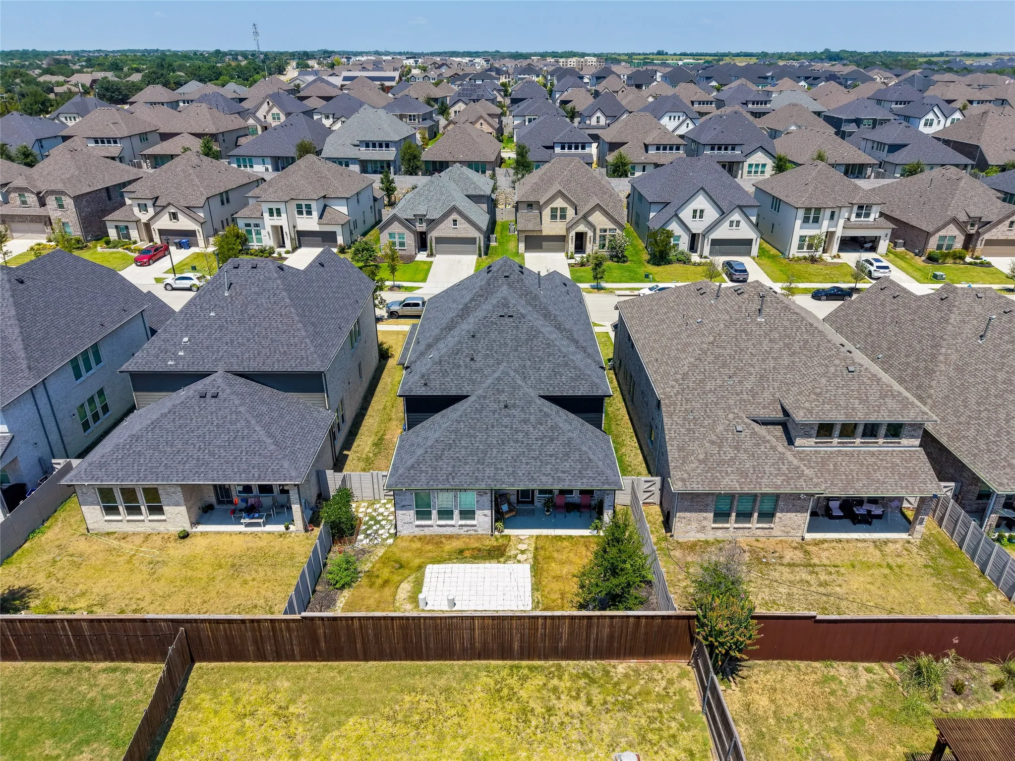 Aerial perspective showcasing a residential neighborhood with uniformly designed homes featuring dark asphalt shingle roofs