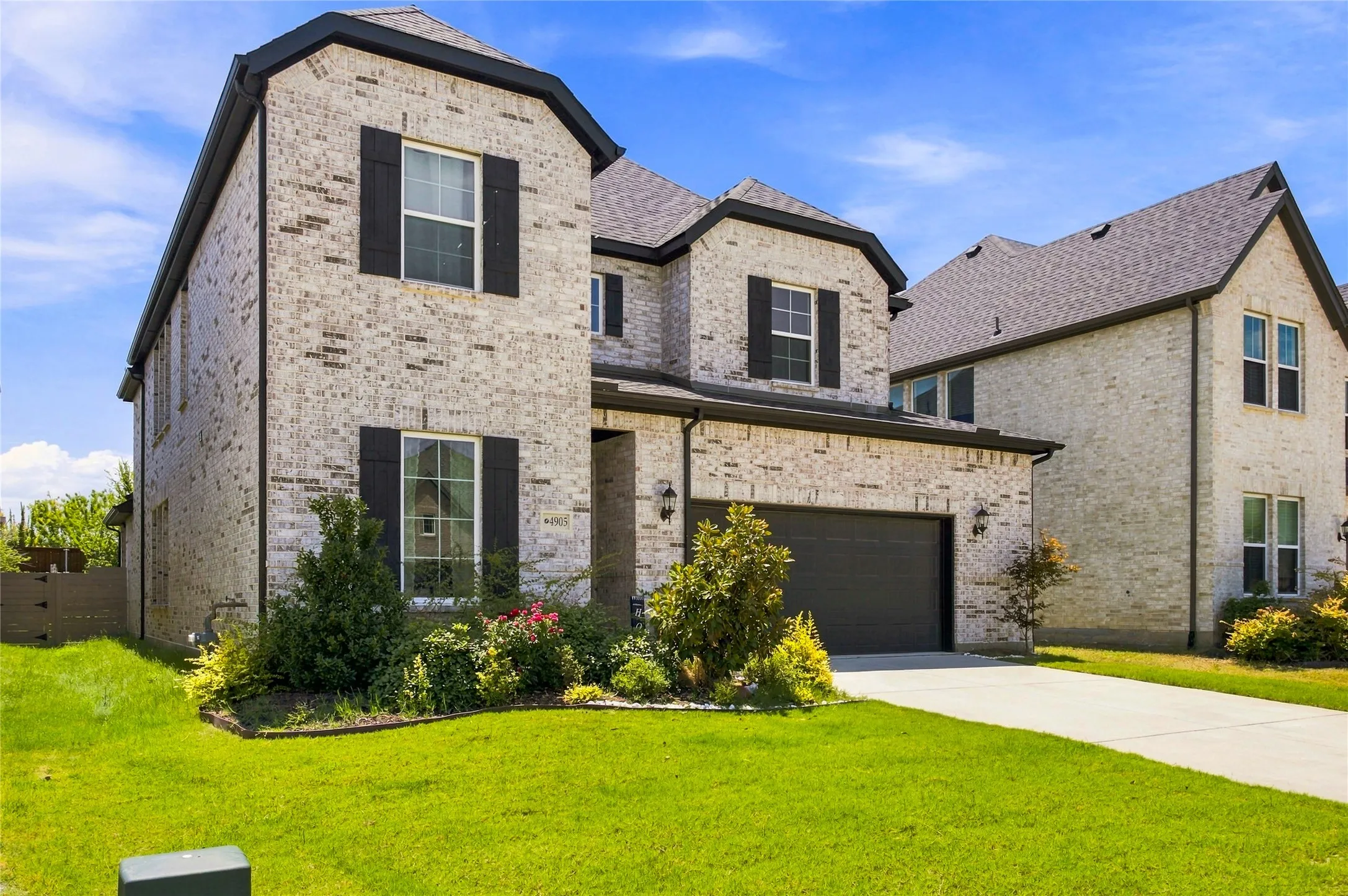 Two-story brick exterior with dark shingle roofing and black shutters