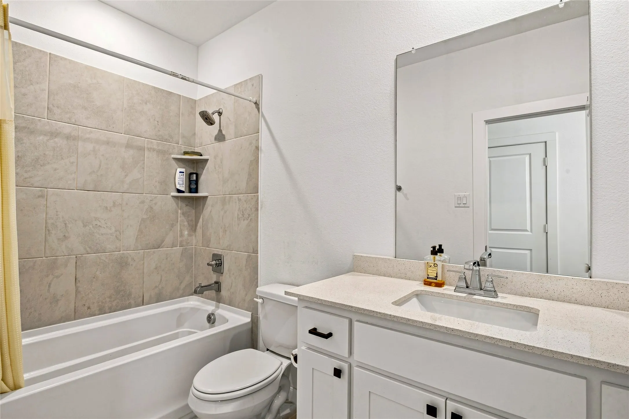 Bathroom featuring a white bathtub with tile surround, built-in shower niche, and shower head