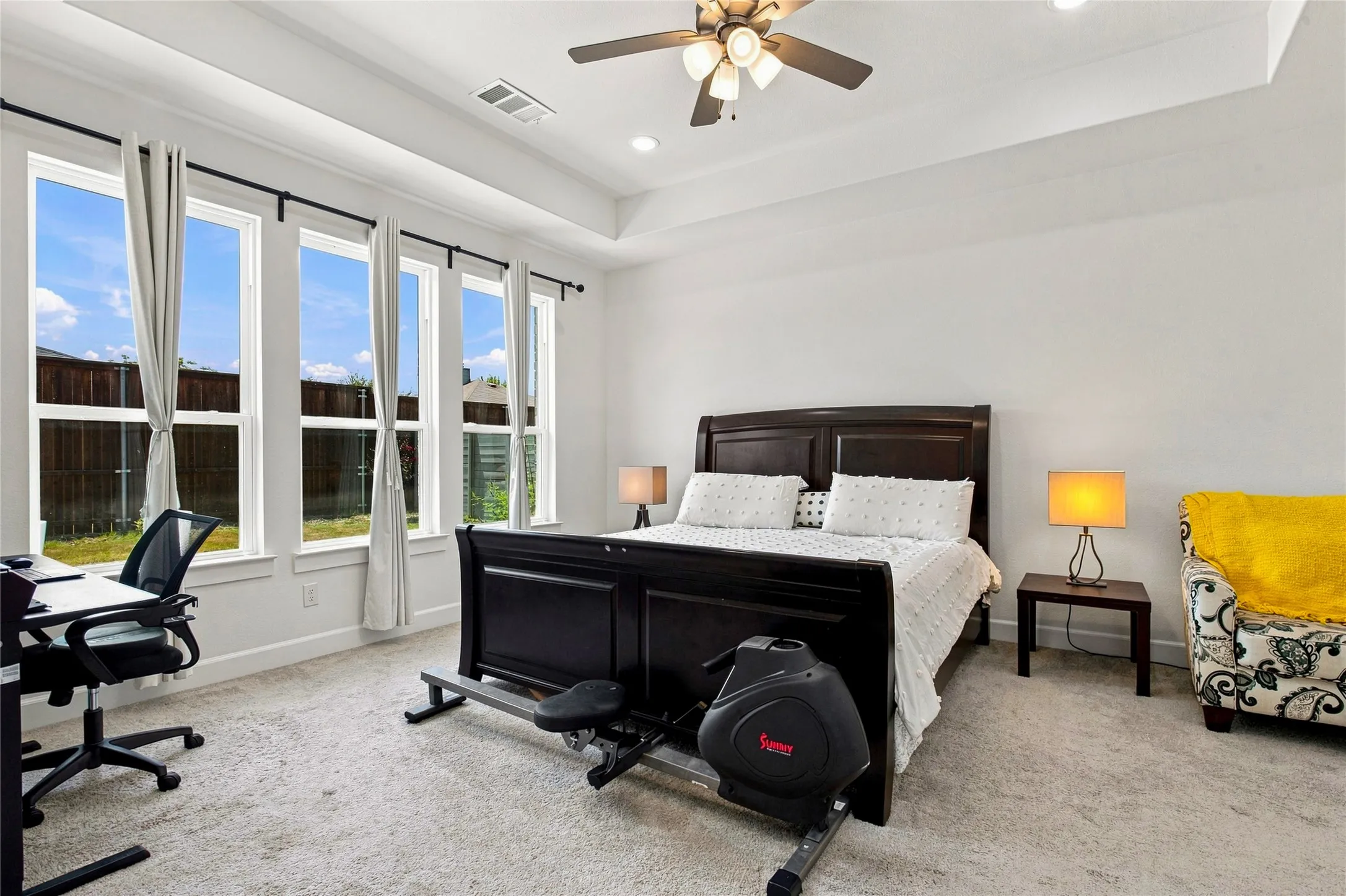 Bright interior space featuring a tray ceiling with a ceiling fan and recessed lighting