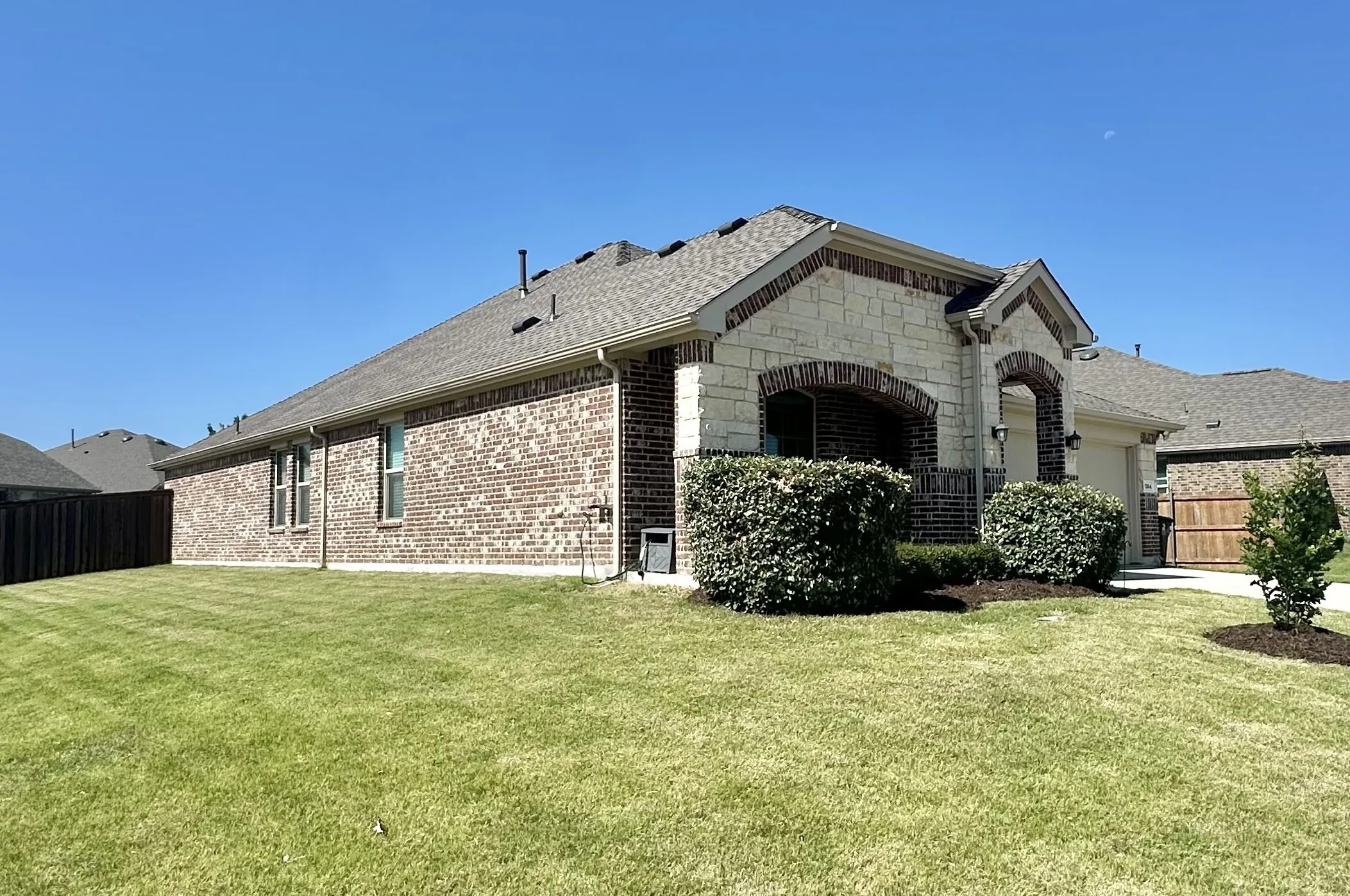 Exterior featuring brick and stone facade, arched entryway, a pitched roof, and an attached garage