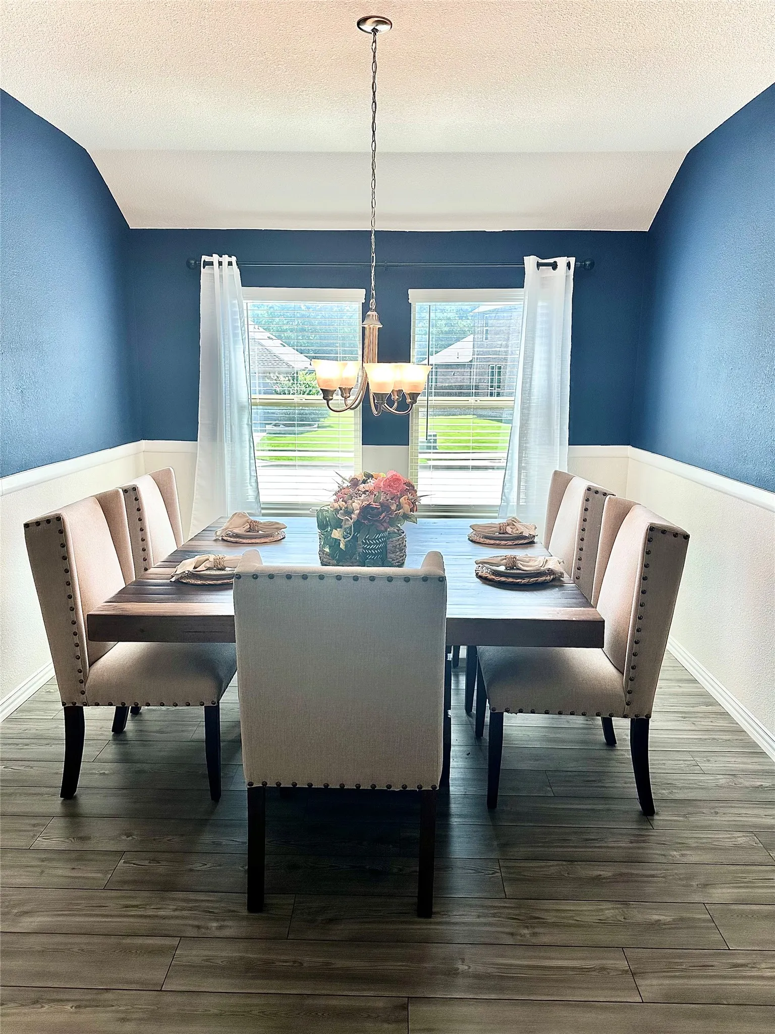 Well-appointed formal dining area featuring beautiful wood-look flooring and a contemporary chandelier, providing a welcoming space for family dinners and memorable celebrations.