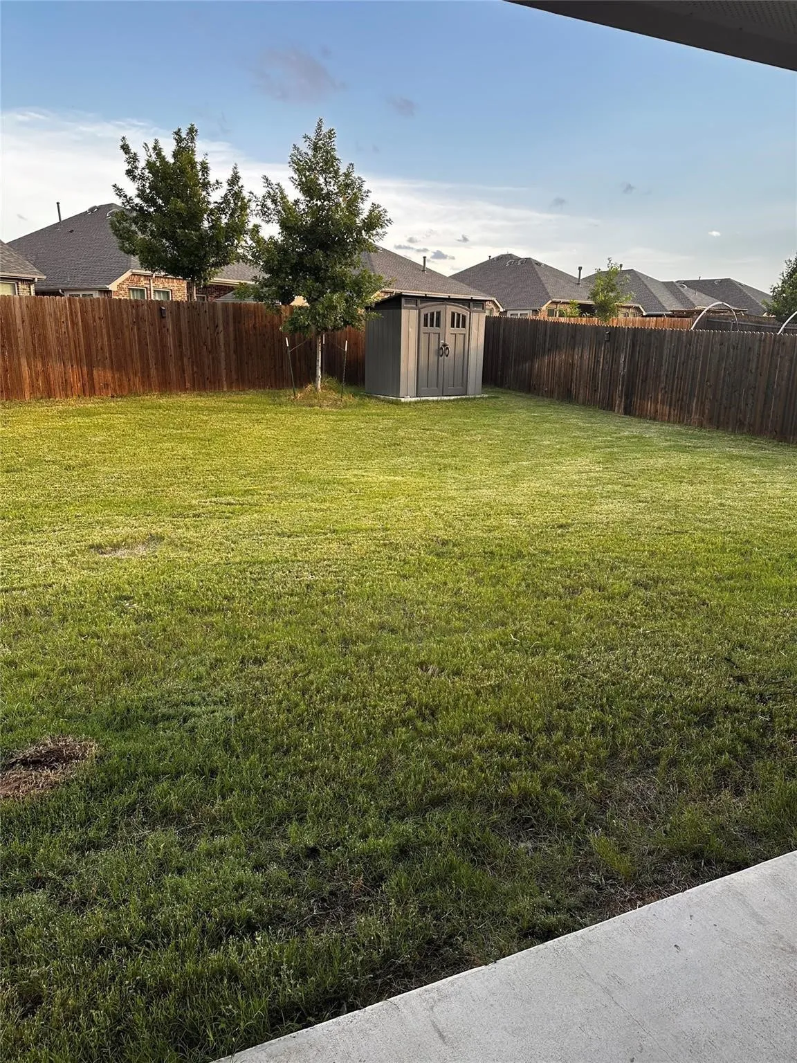 Generous backyard retreat offering a large grassy area, privacy fencing, and plenty of space for gatherings, pets, and outdoor enjoyment that includes a storage shed.