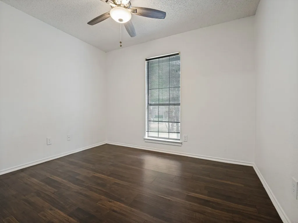 Wood-finish flooring, single window with blinds, ceiling fan, and white walls