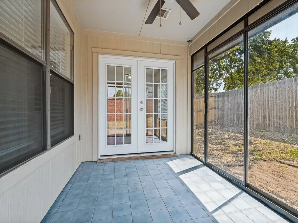 Screened patio featuring a ceiling fan, tiled flooring, double French doors, and large sliding windows