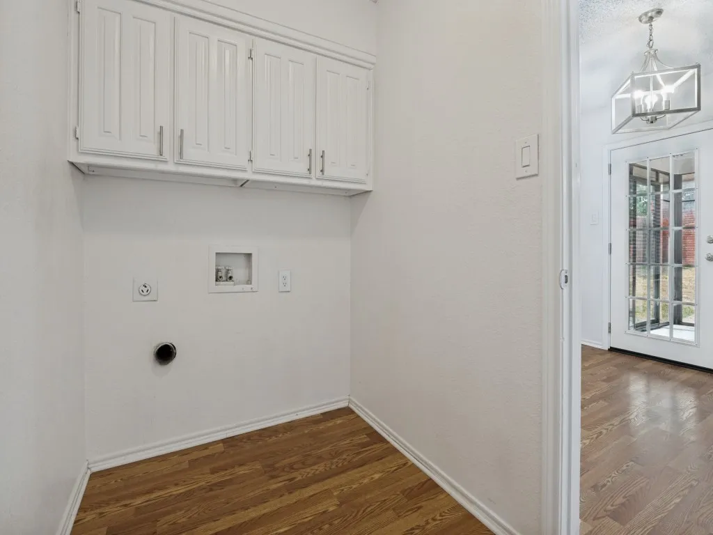 Utility area featuring wood-finish flooring, white cabinetry, and a geometric semi-flush mount fixture