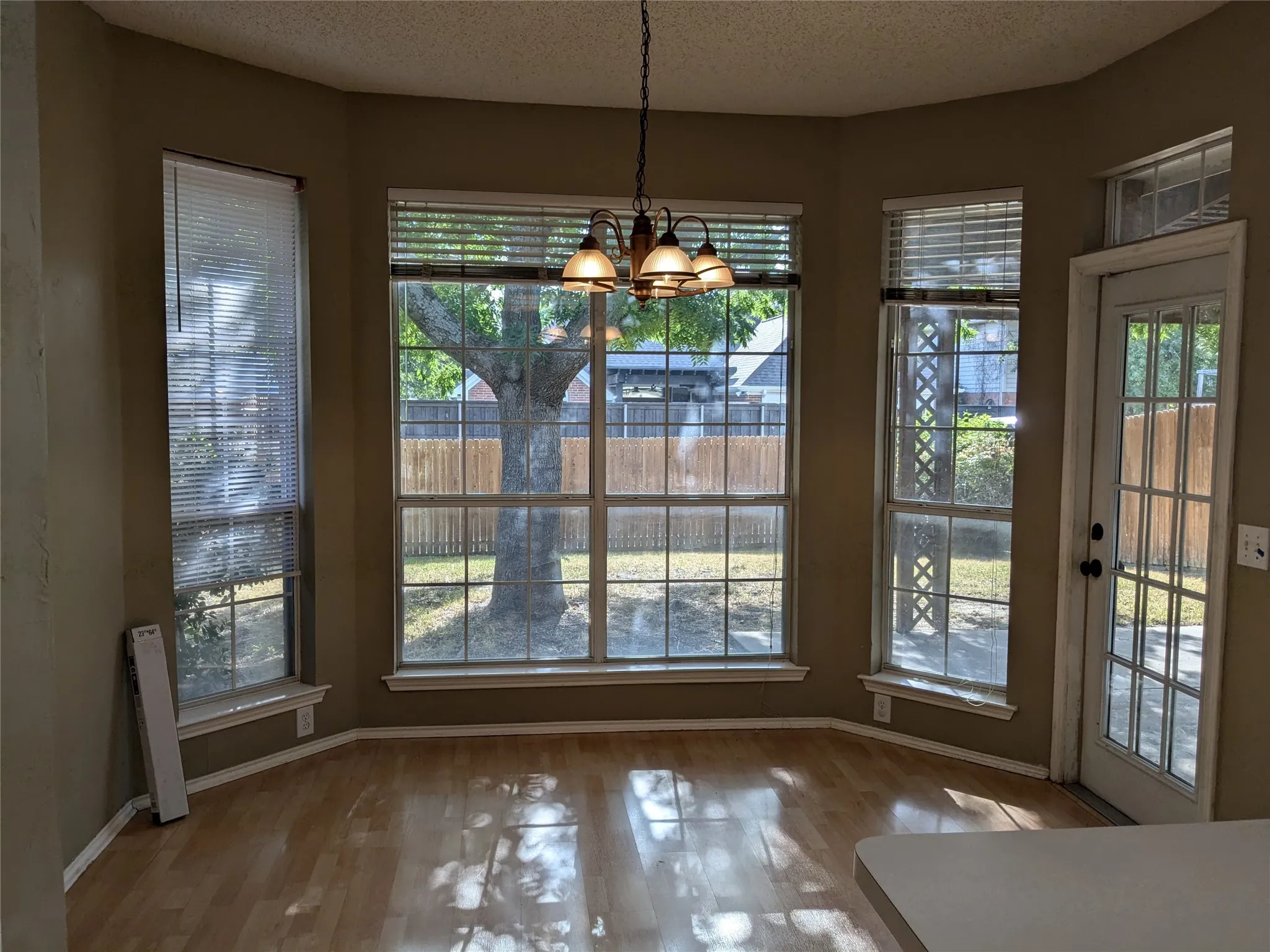 Bay window with multiple large windows, wood-finish flooring, and overhead chandelier
