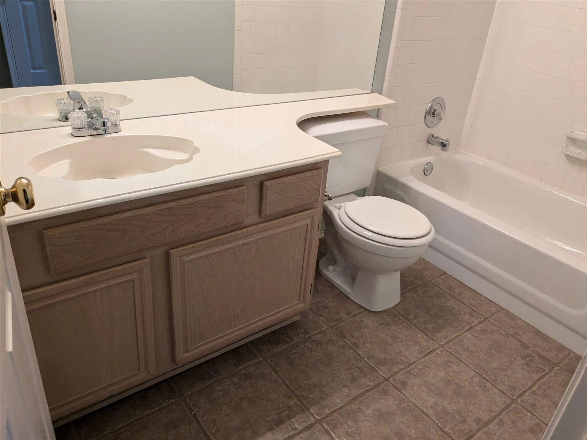 Wood-finish vanity with integrated sink, expansive countertop, and large wall-mounted mirror