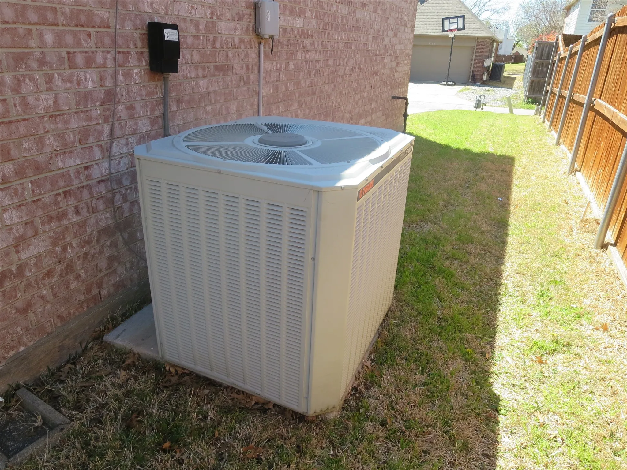 Exterior brick siding with a concrete pad supporting the outdoor unit