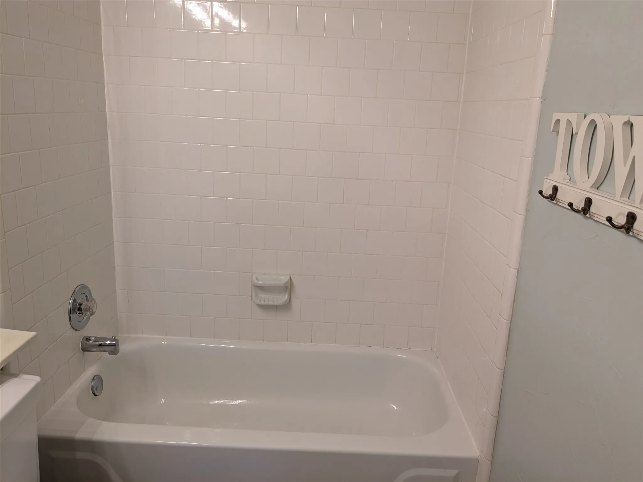 White ceramic subway tile surround with a built-in tub and chrome fixtures
