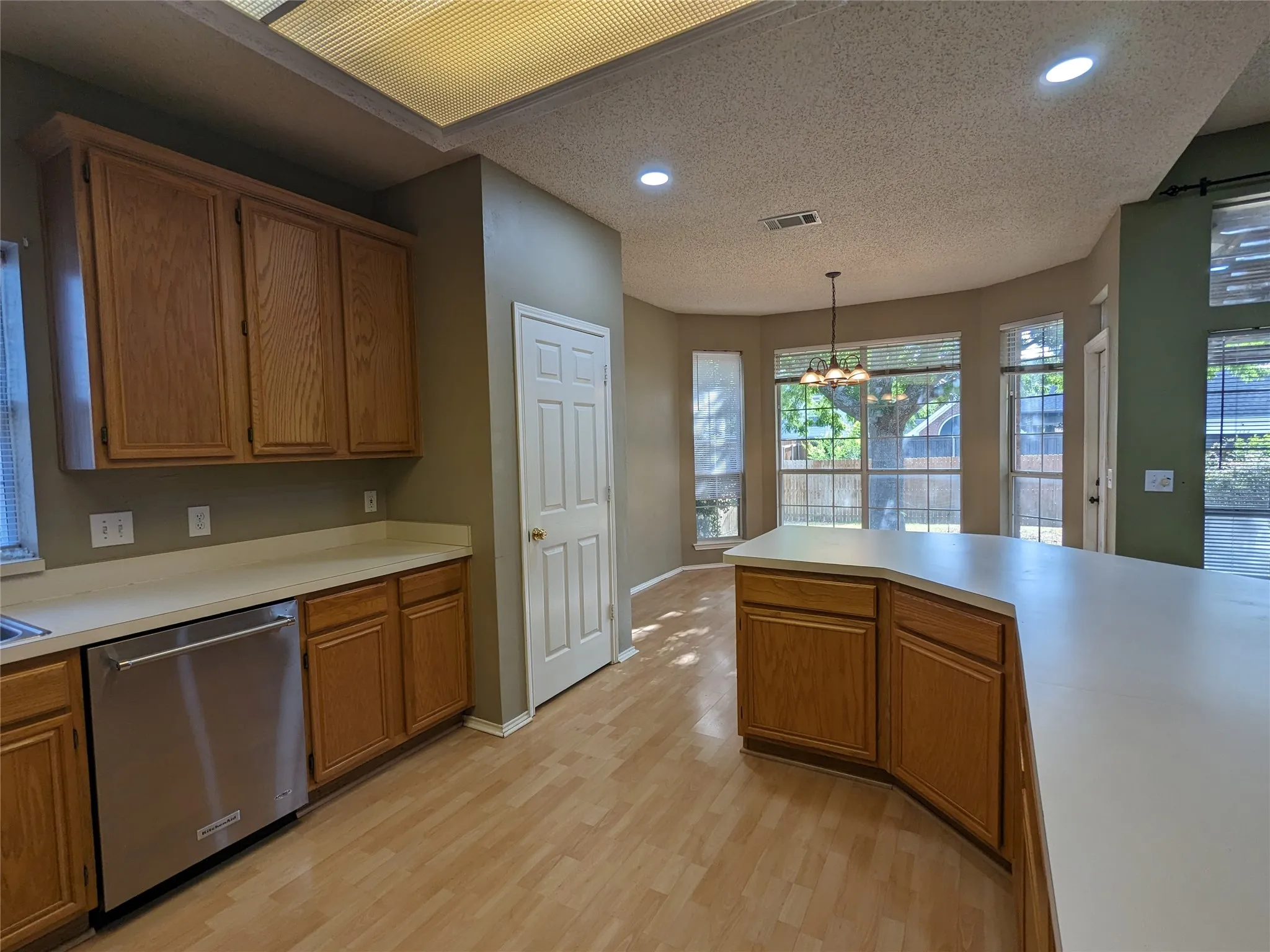 Kitchen featuring wood-finish flooring, recessed lighting, wood cabinetry, and a stainless steel dishwasher