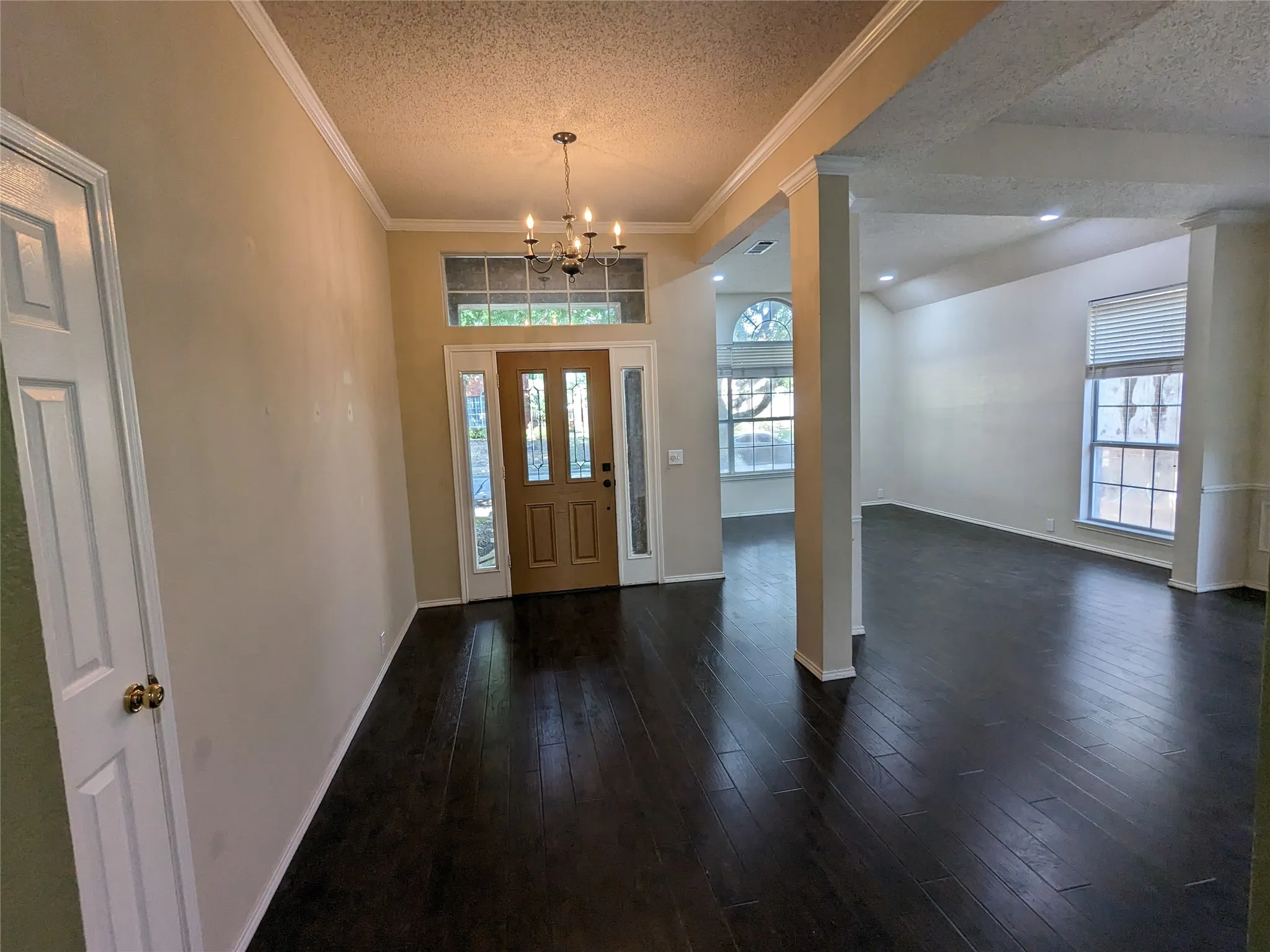 Wood-finish flooring throughout, entry chandelier, transom window, arched window, and recessed lighting