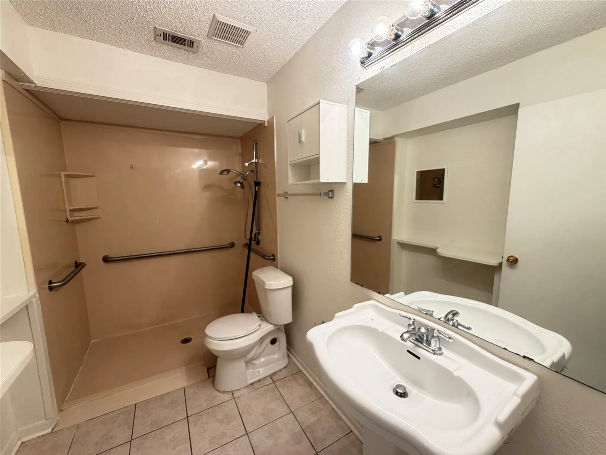 Pedestal sink with chrome fixtures, full-width wall mirror, and vanity lighting
