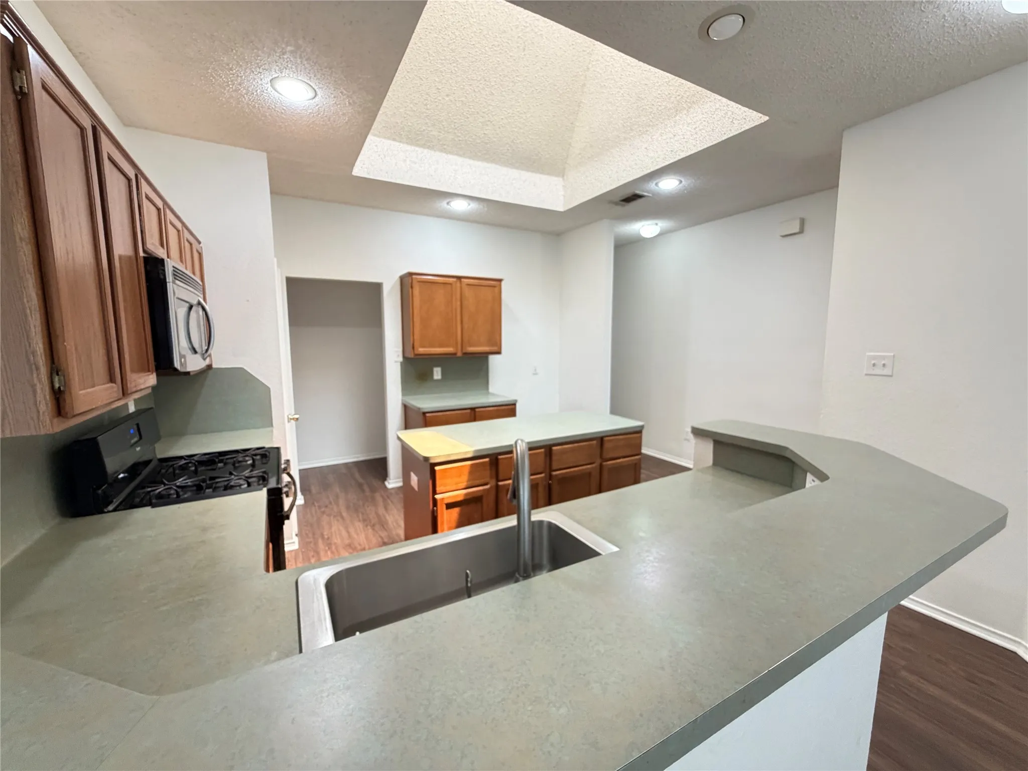 Kitchen featuring wood-finish cabinetry, a stainless steel sink, an integrated gas range, a built-in microwave, and recessed lighting