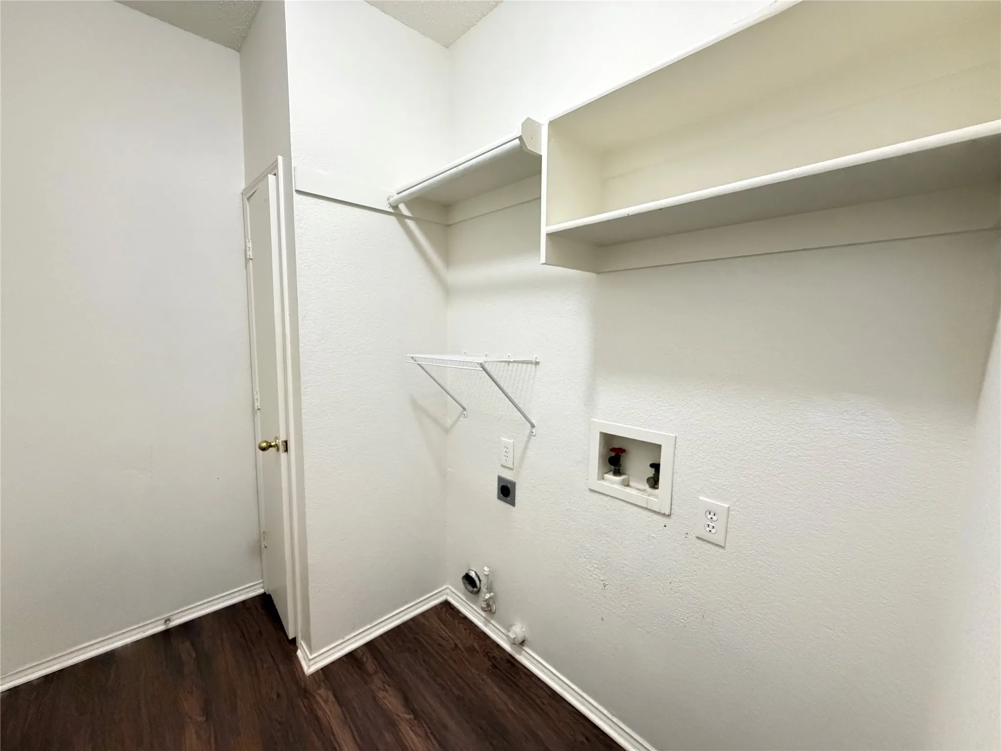Laundry area featuring wood-finish flooring, built-in shelving, and utility hookups