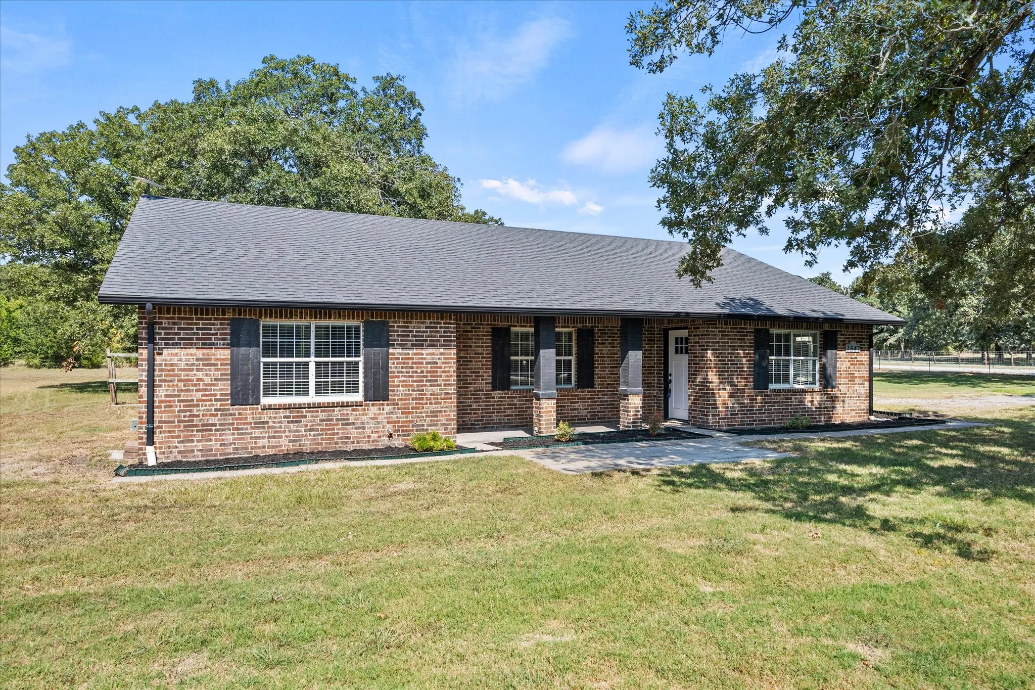 Charming brick residence featuring a gabled roof with architectural detail, expansive front-facing windows, and a covered entry portico