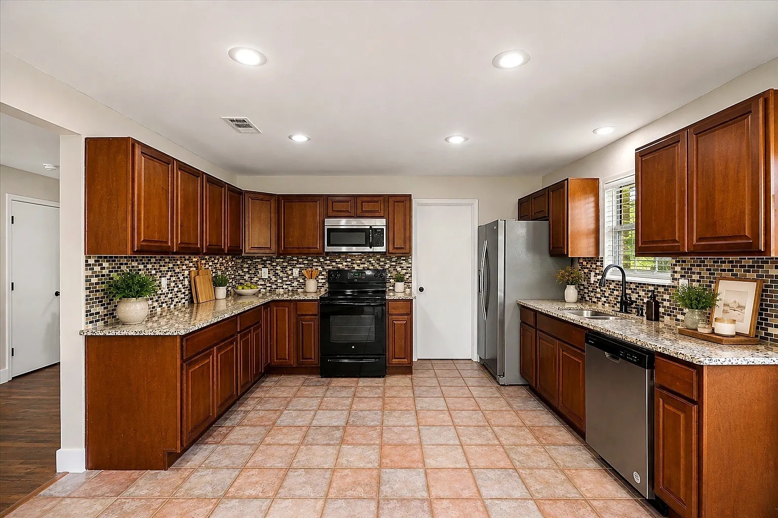 U-shaped kitchen featuring wood cabinetry, granite countertops, tile backsplash, and recessed lighting