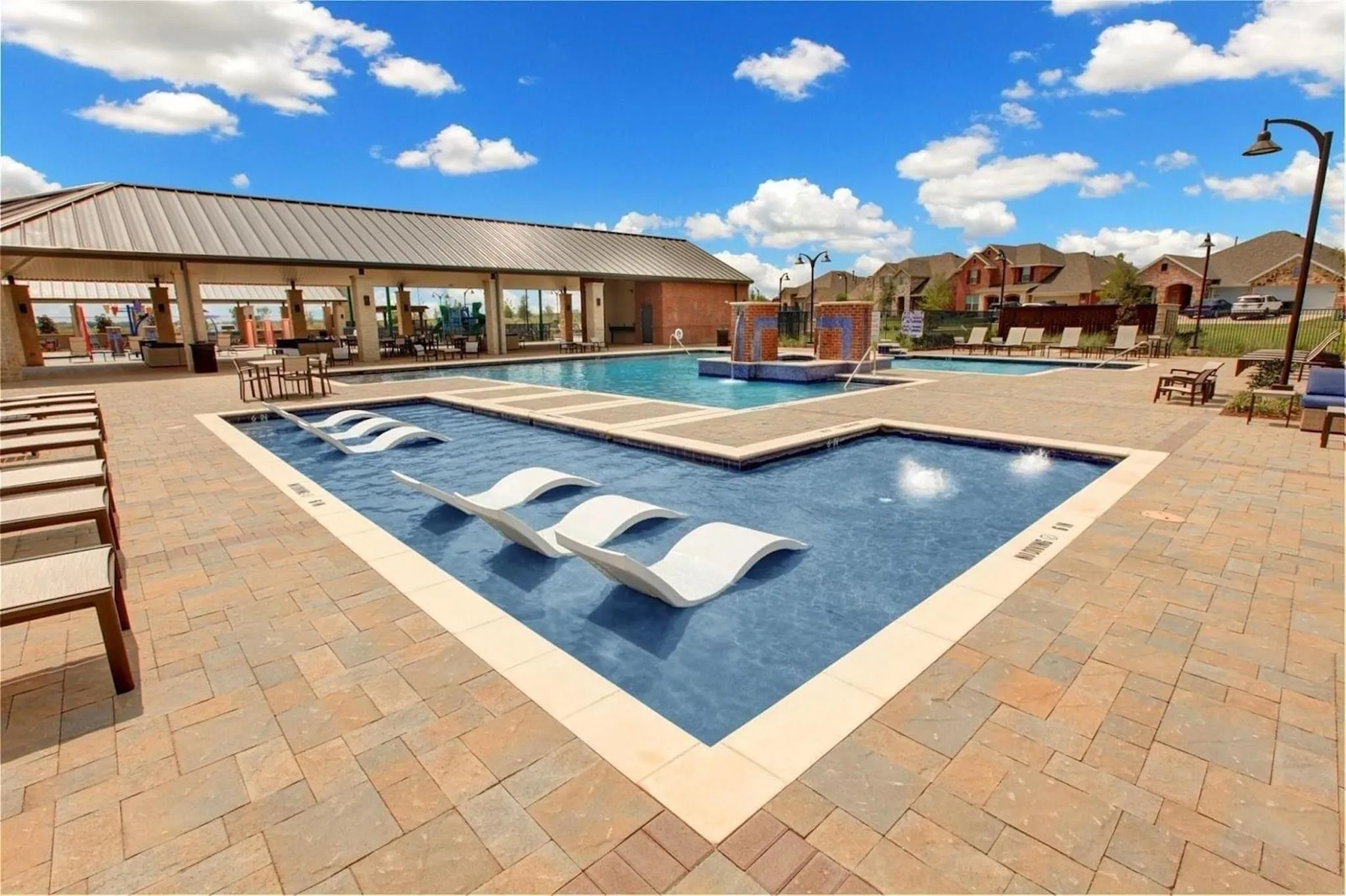 Expansive paver patio surrounding a multi-level pool with integrated tanning ledges