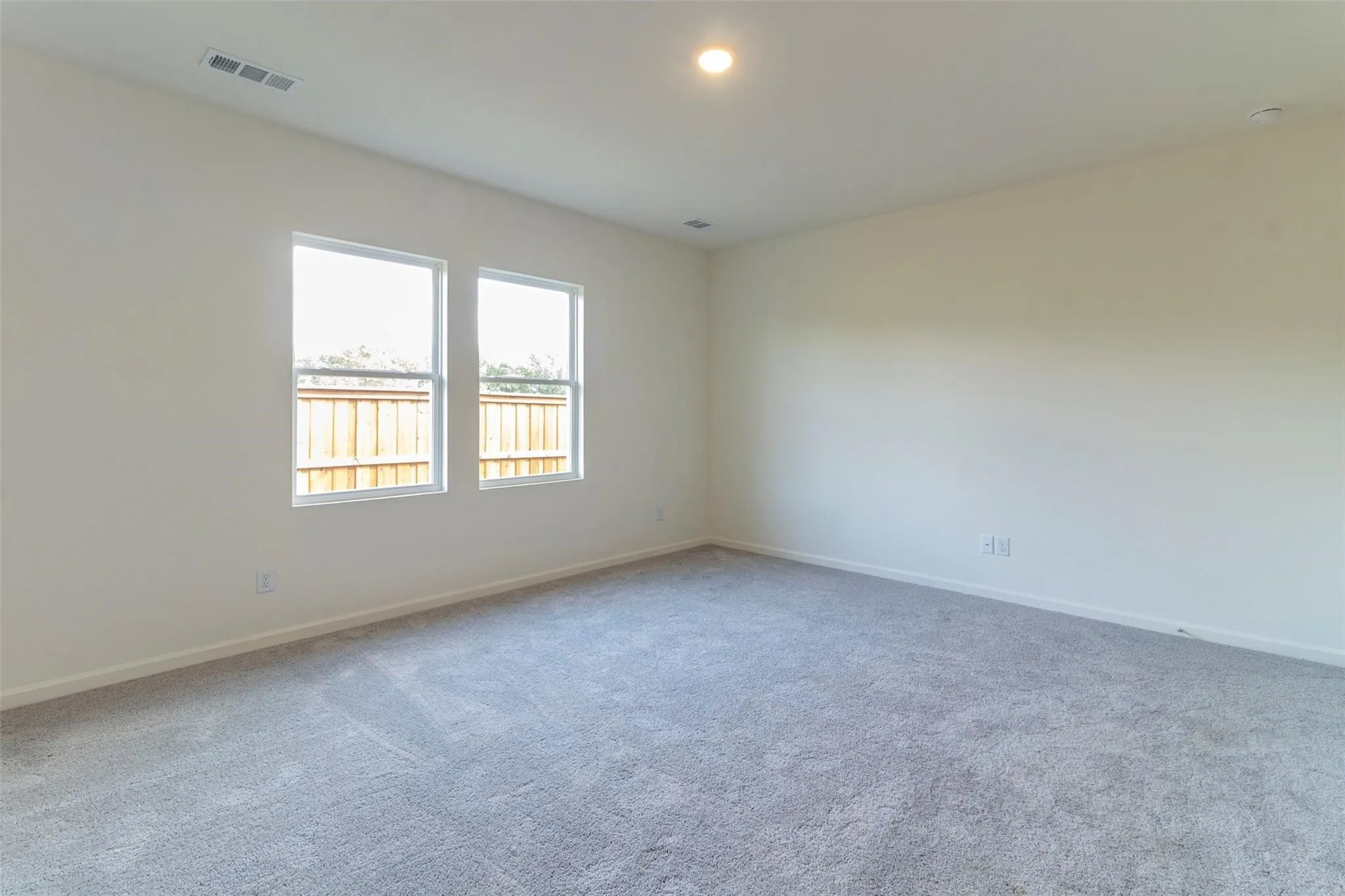 Recessed lighting, light gray carpeting, two windows with white trim, and a white ceiling