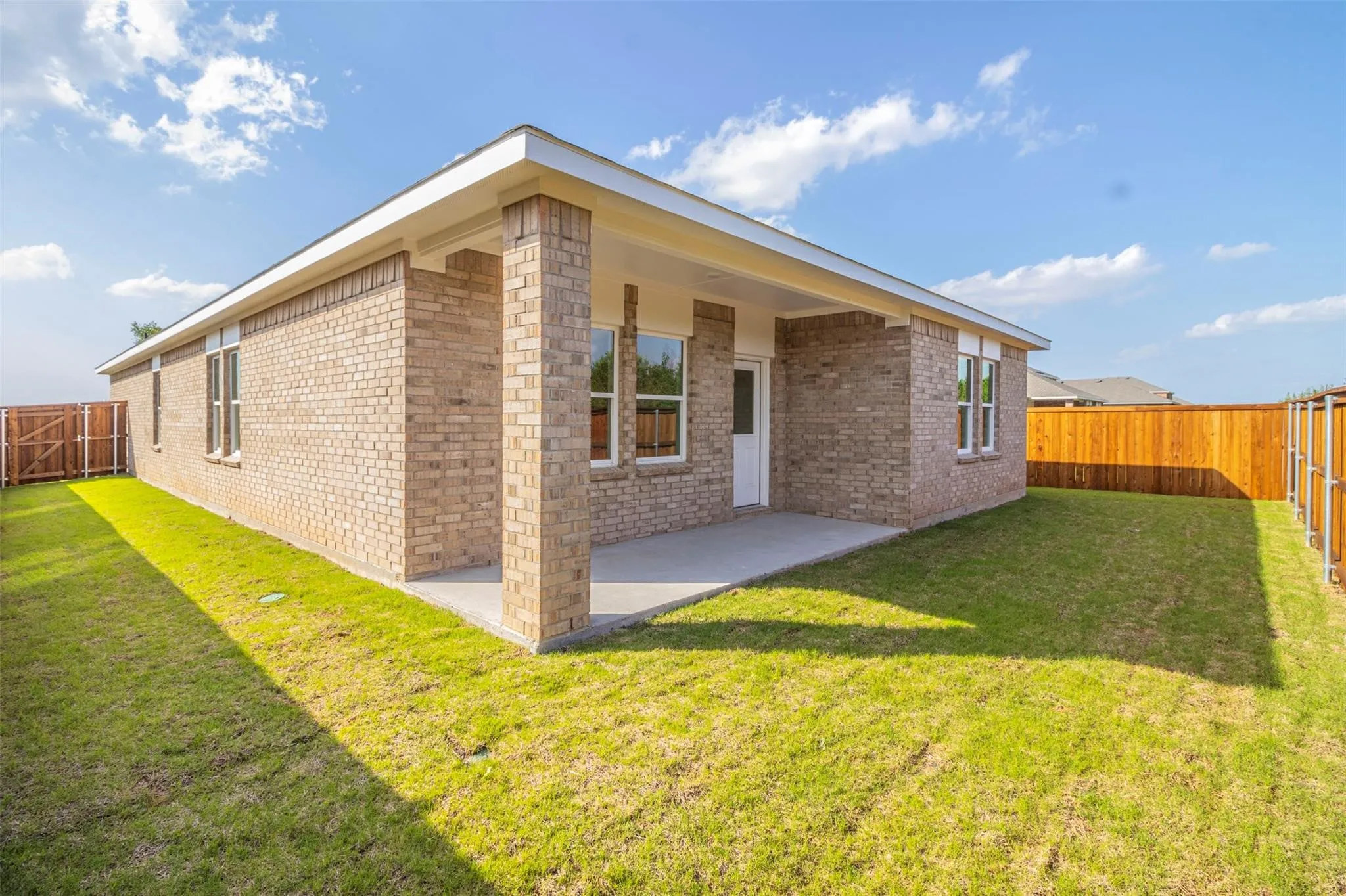 Brick exterior, covered patio, concrete patio surface, wood privacy fencing, multiple windows