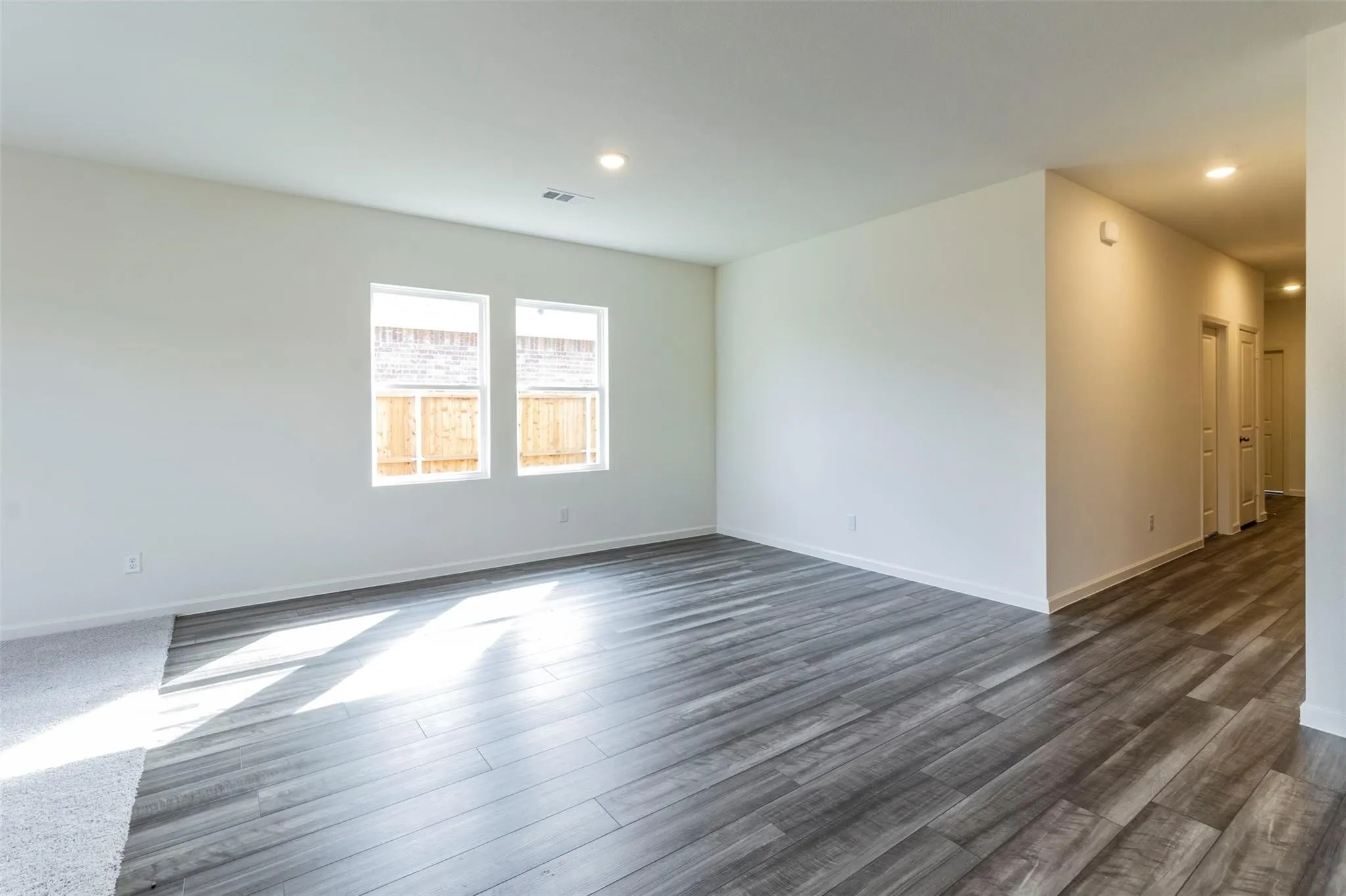 Spacious room featuring wood-finish flooring, recessed lighting, and multiple windows