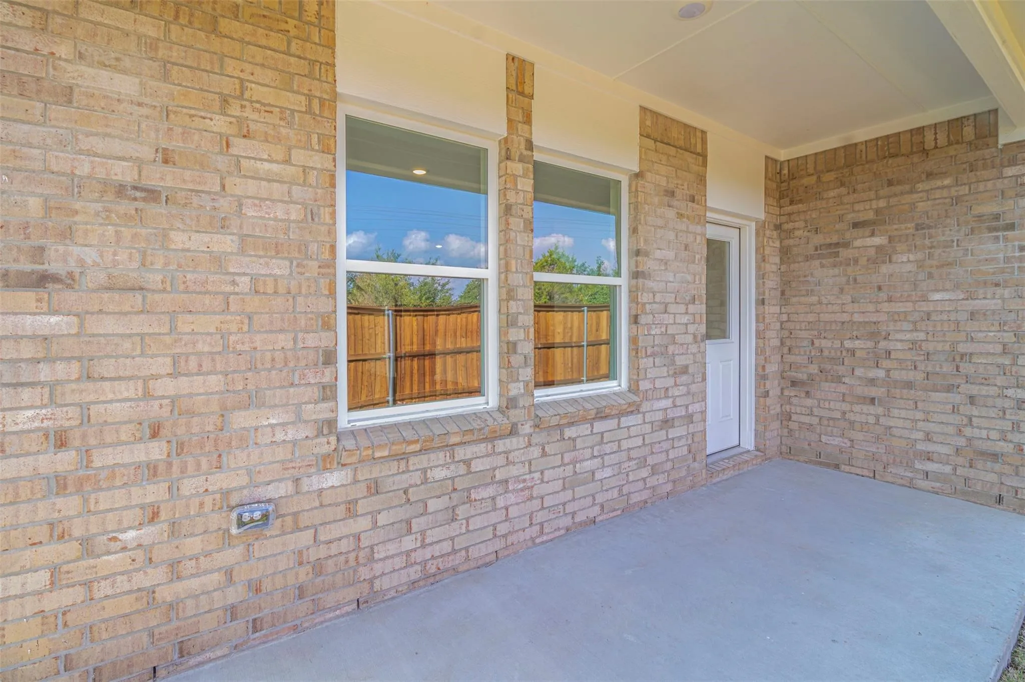 Brick exterior with a covered patio, concrete flooring, and an exterior door