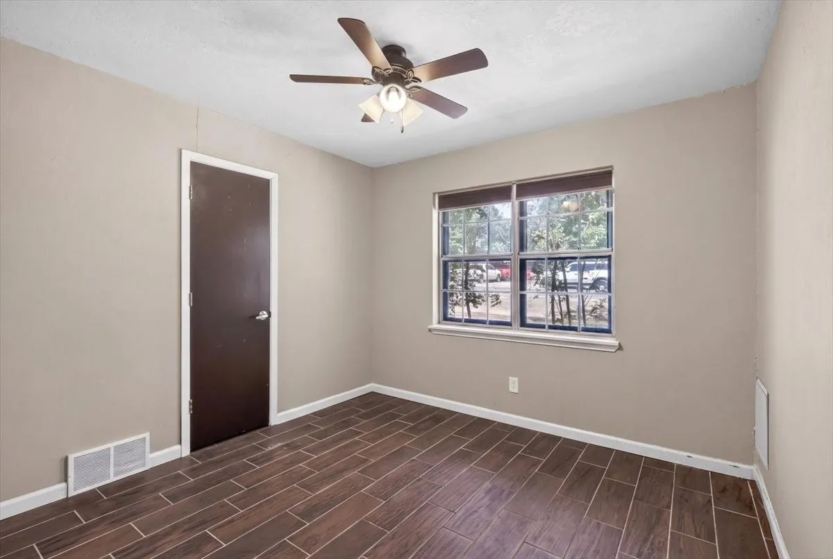 Secondary bedroom with ceiling fan, wood looking ceramic tile flooring and windows for natural light