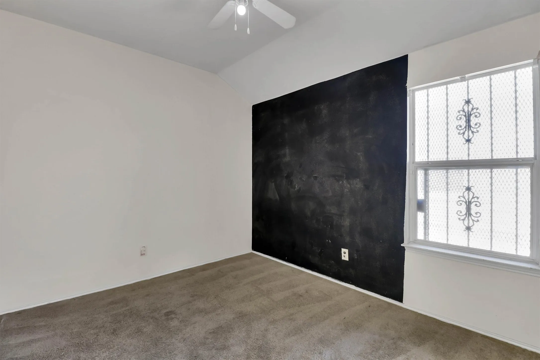 Carpeted flooring, a white ceiling fan, and a prominent chalk accent wall