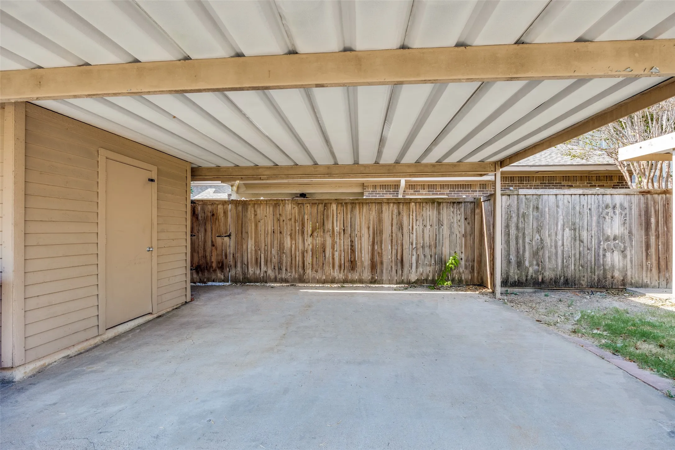 Covered carport offers private back entrance with an attached storage shed