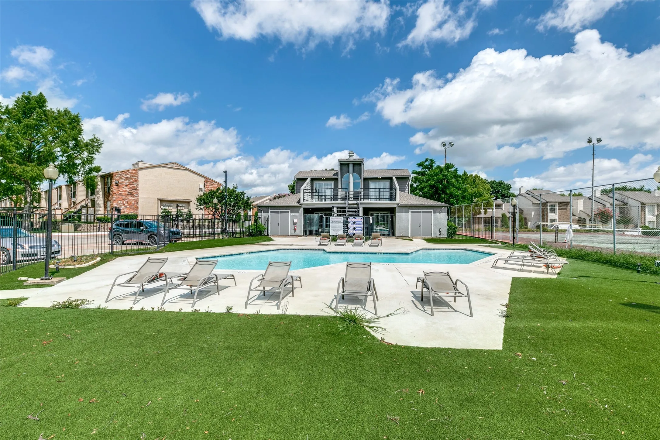 Community swimming pool with surrounding concrete decking and artificial turf