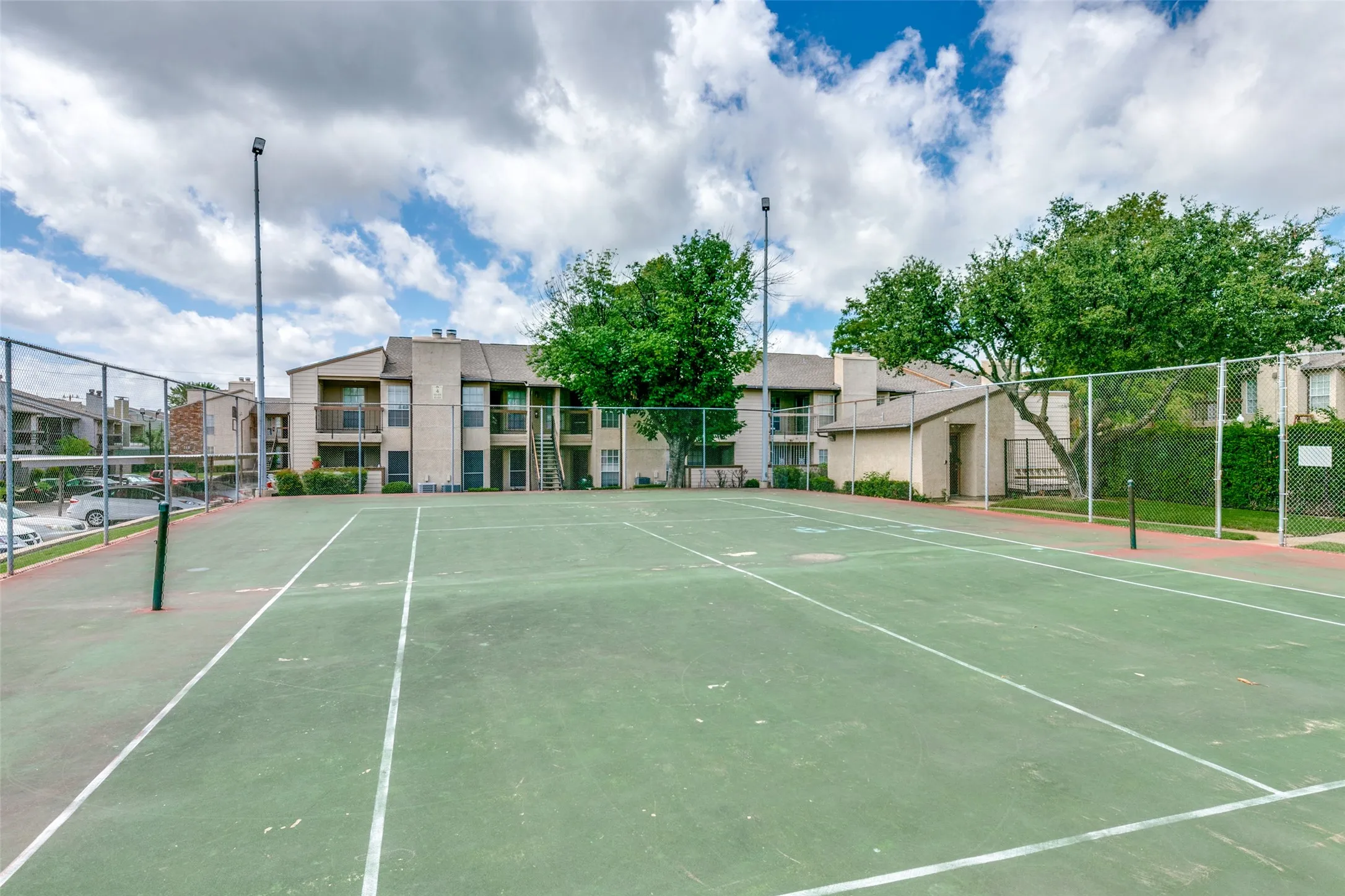Tennis court with perimeter fencing and tall lighting fixtures