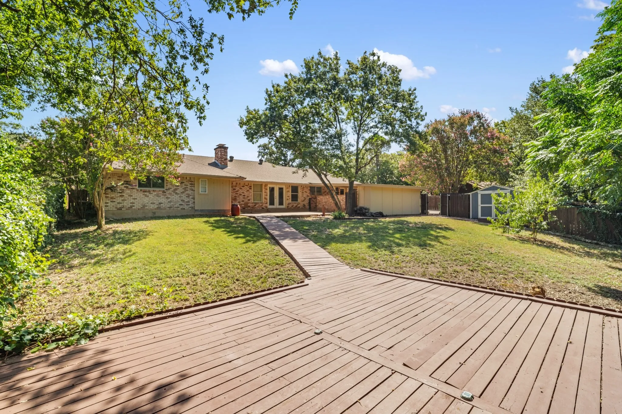 Wood Patio with view of back of home, storage off the carport and a storage building