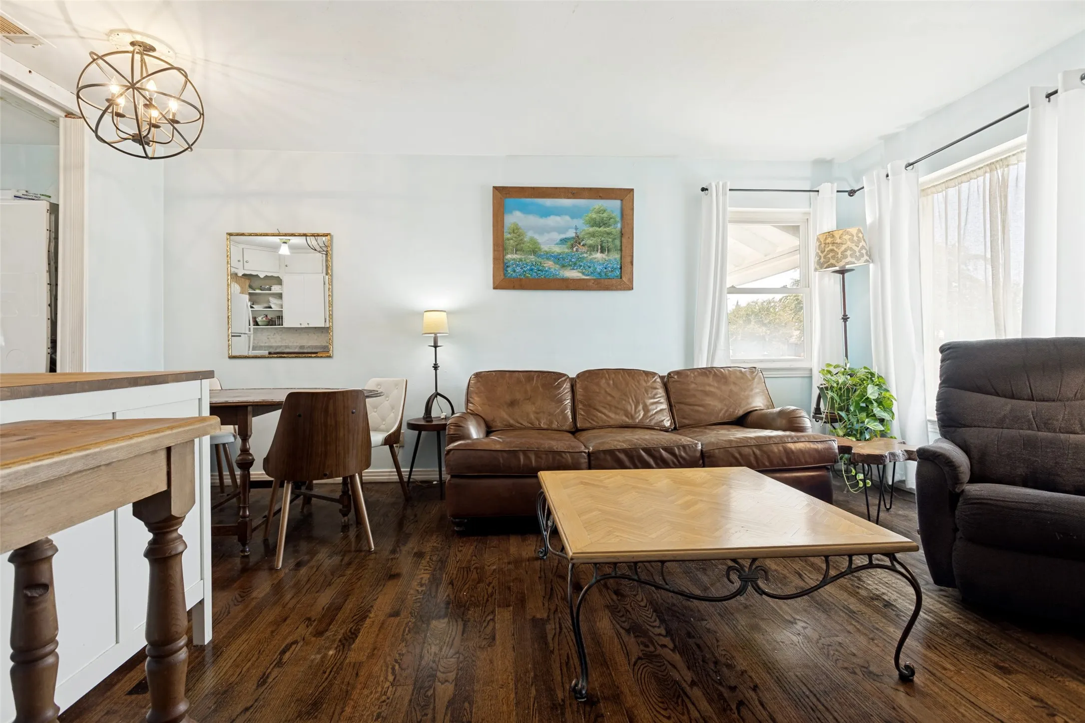 Rich wood-finish flooring throughout, light blue wall paint, white trim, and multiple windows