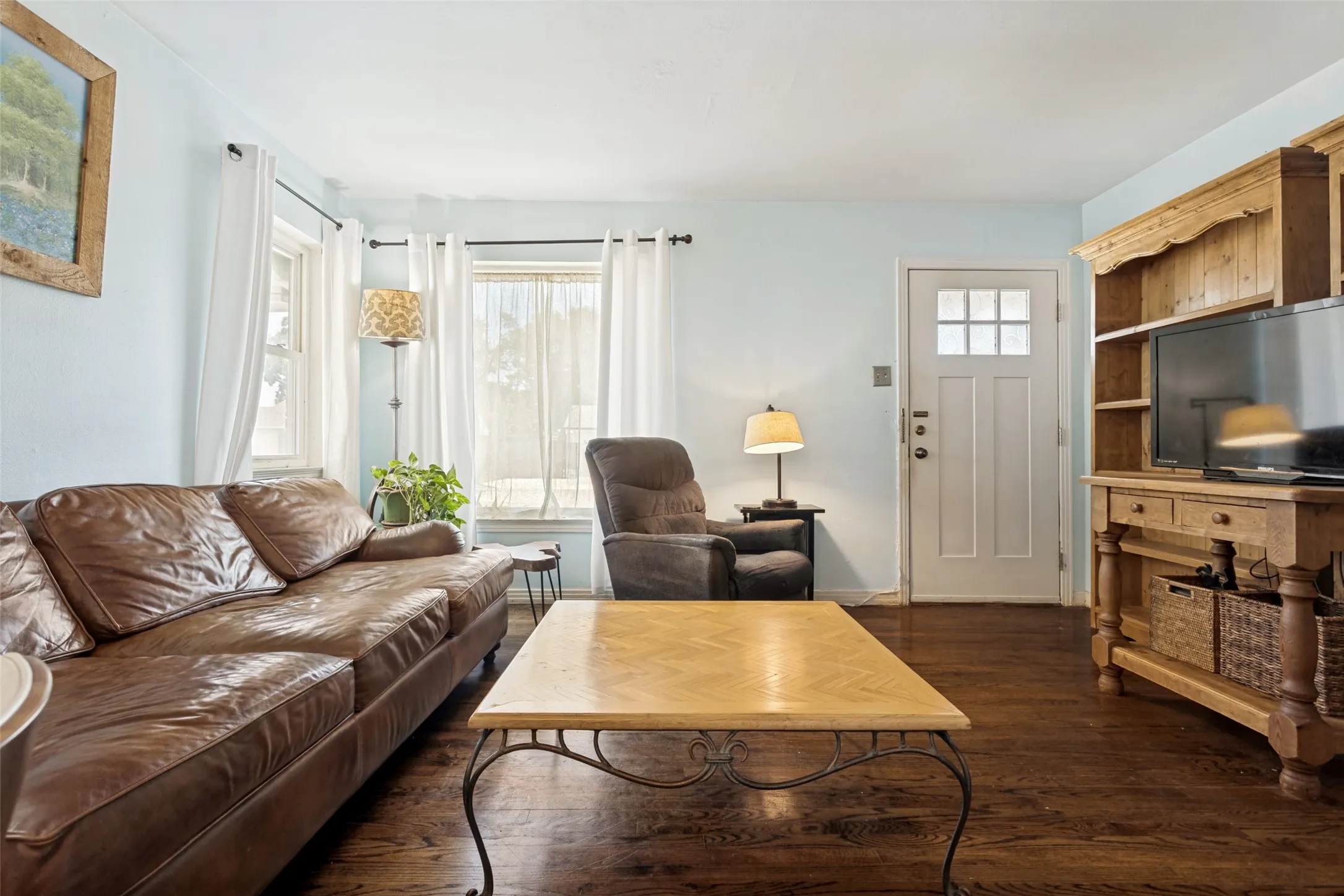 Hardwood flooring throughout, multiple windows with white trim, and a white paneled door with glass inserts
