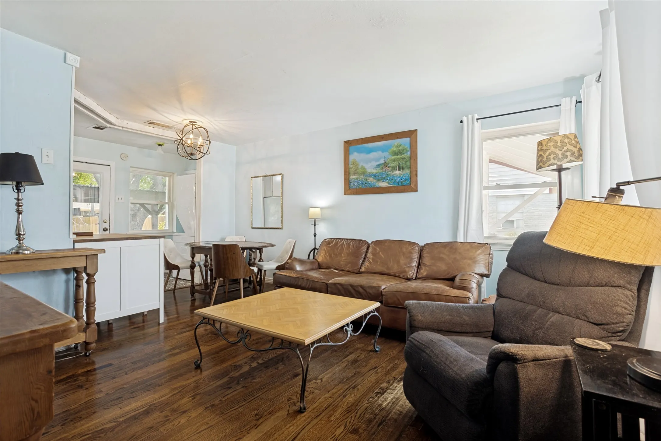 Wood-finish flooring throughout, light blue walls, and a round light fixture with an open design