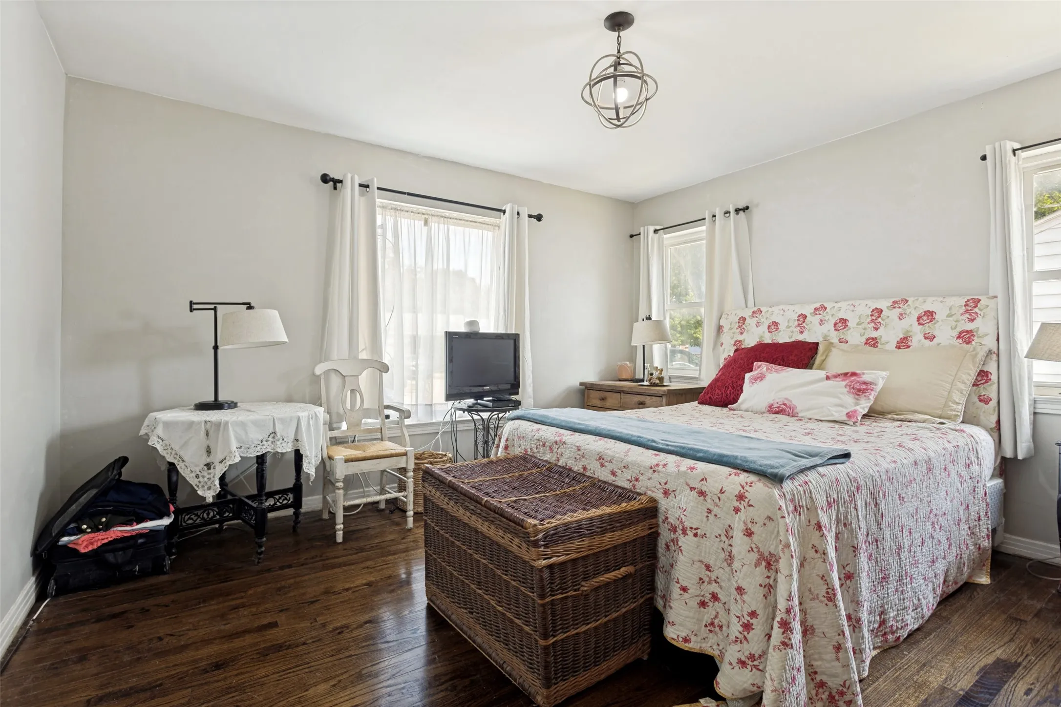 Hardwood flooring, light-toned walls, ceiling-mounted light fixture, window with drapery, and a second window