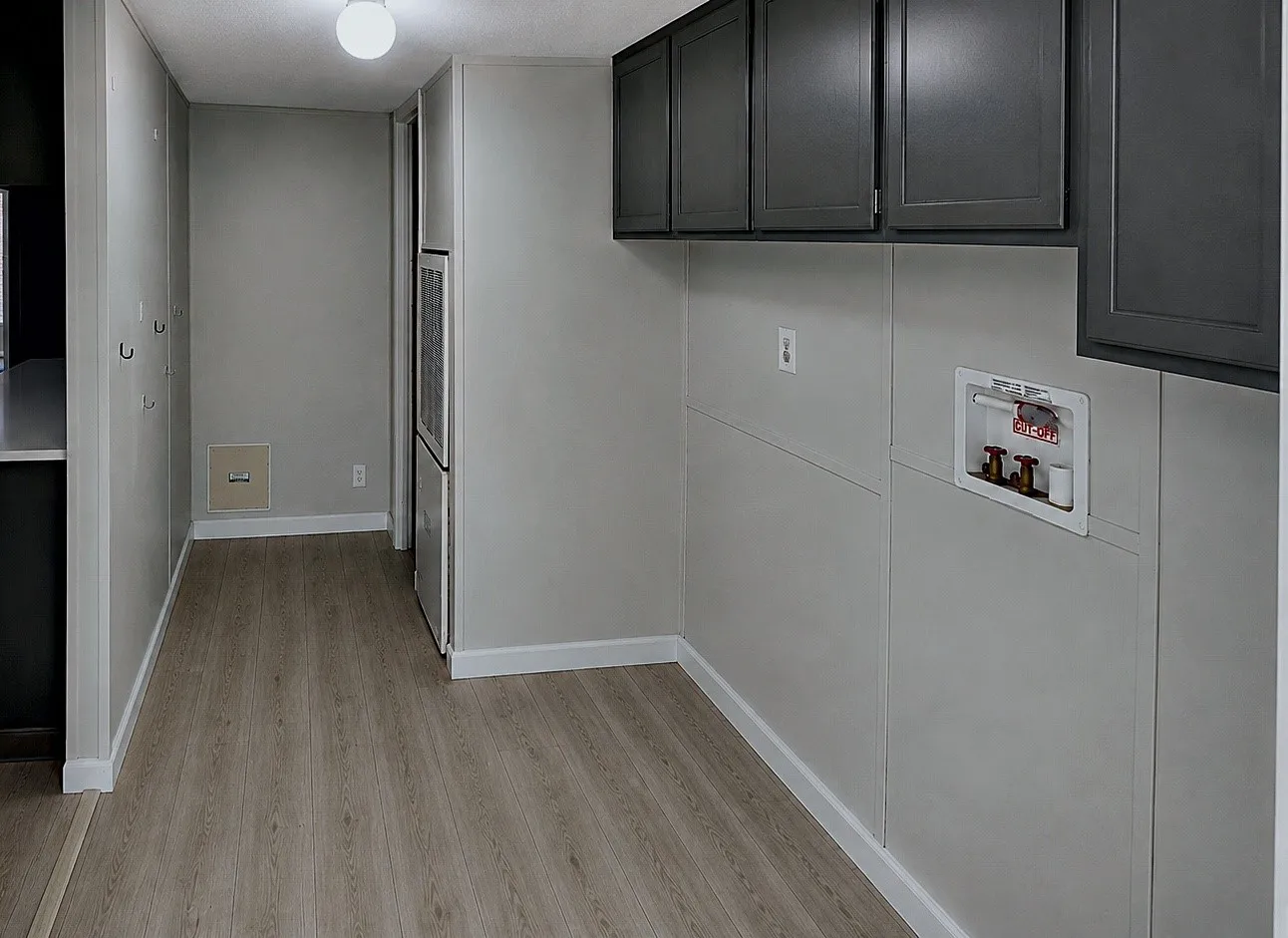 Light wood-finish flooring, overhead lighting, wall-mounted storage hooks, and dark upper cabinetry