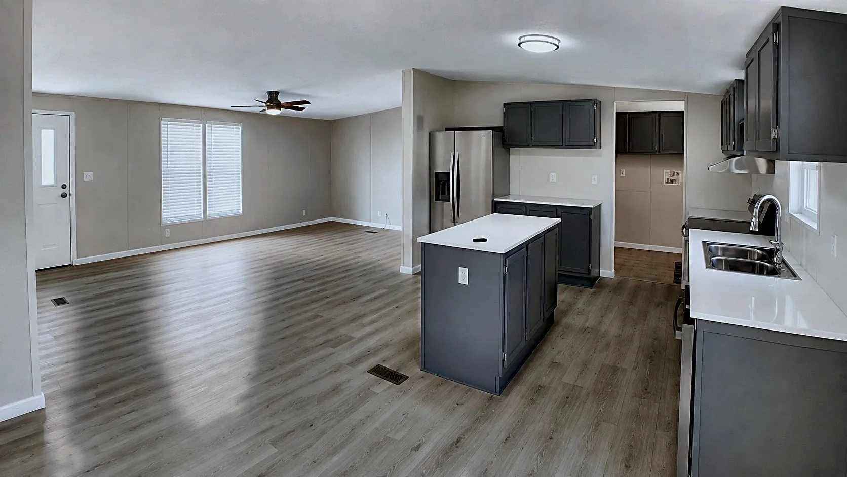 Open-concept living area with wood-finish flooring, a ceiling fan, and ample natural light