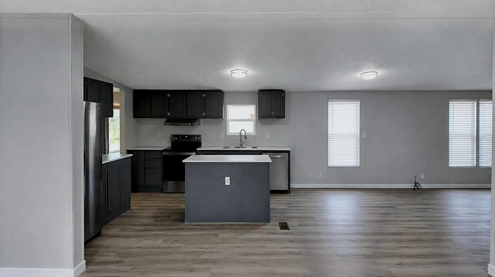 Kitchen featuring dark cabinetry, stainless steel appliances, a center island, and light countertops