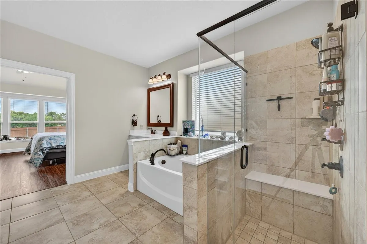 Bathroom featuring a glass-enclosed shower with tile surround and integrated bench
