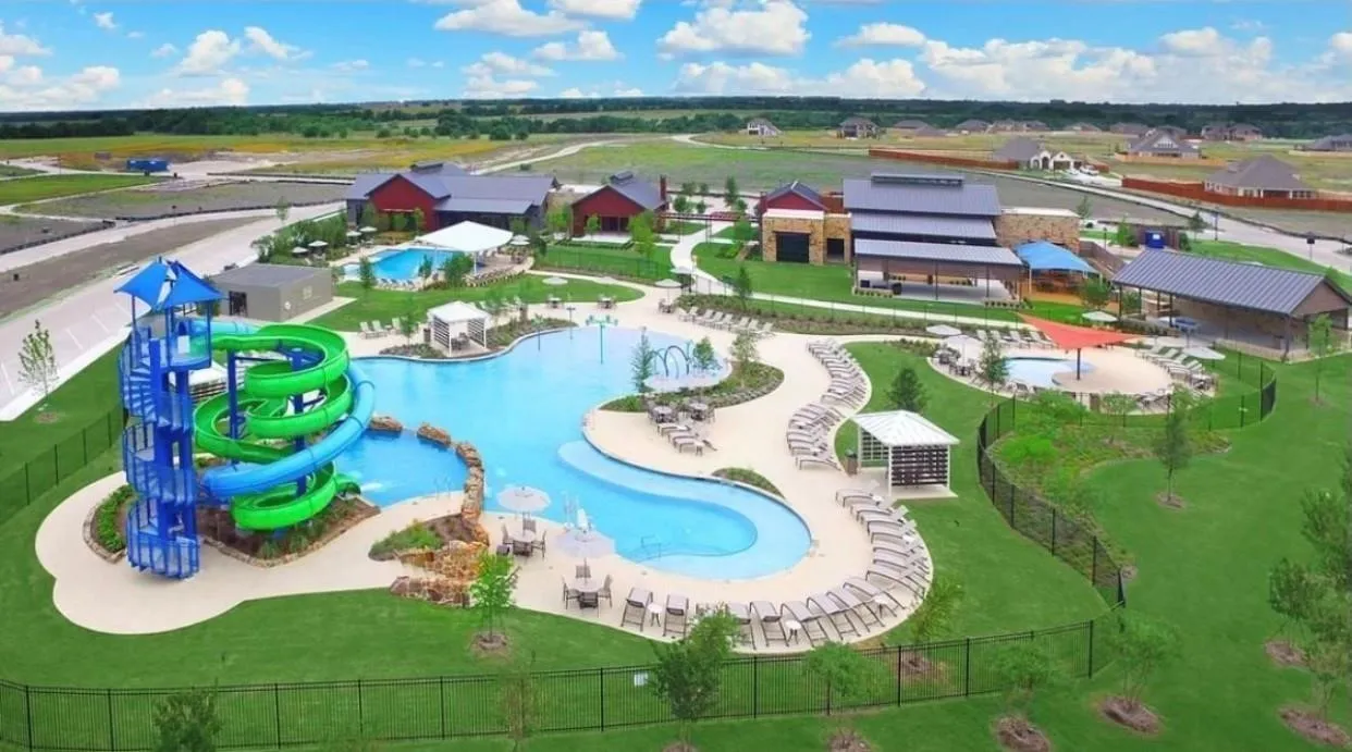 Community amenity center featuring a large resort-style pool with a spiral water slide, multiple lounge areas, a separate lap pool, and a shaded structure with additional seating