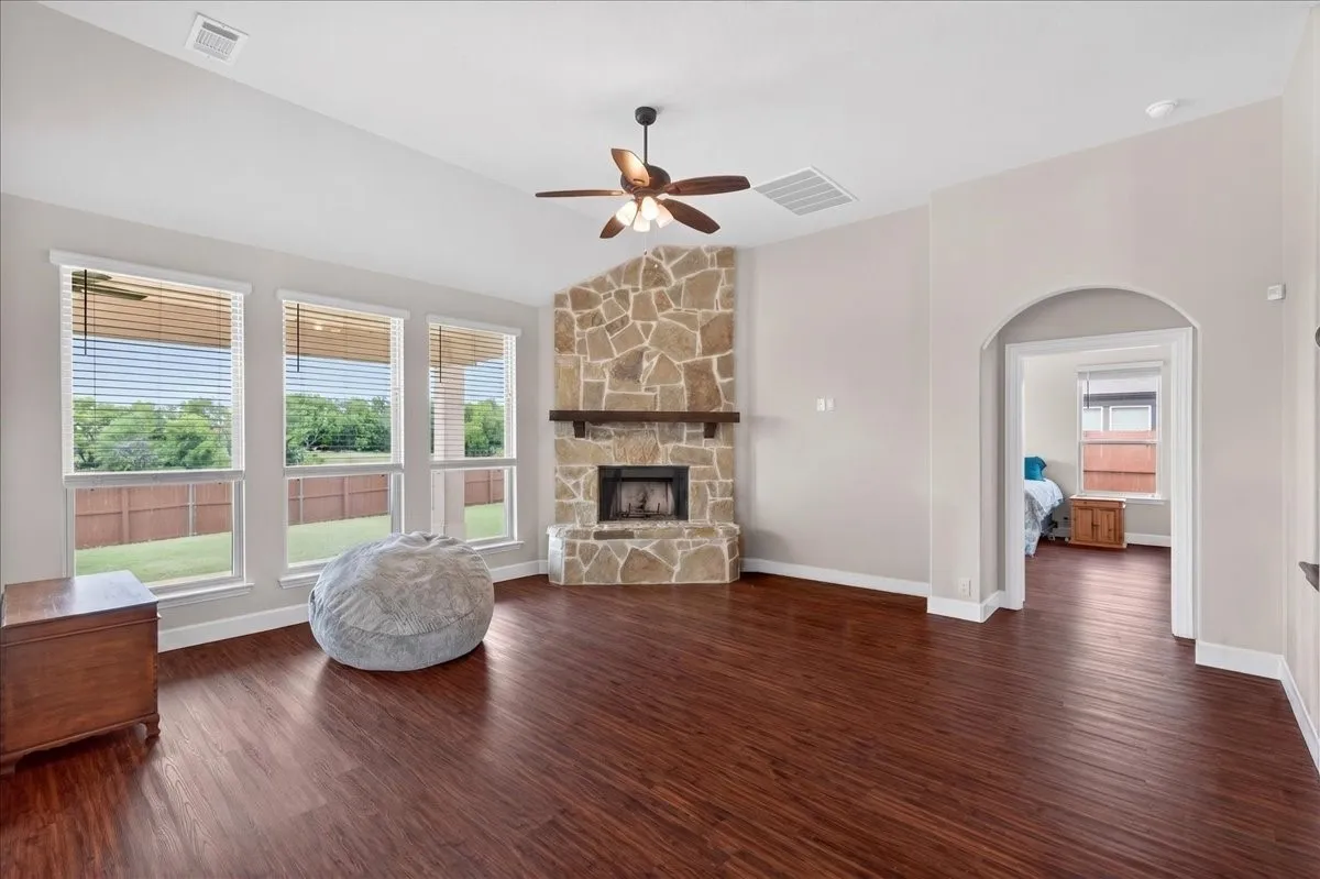 Spacious interior featuring wood-finish flooring, a vaulted ceiling, and a stone-faced fireplace with a wood mantel