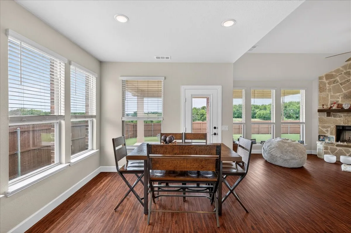 Open-concept living space featuring wood-finish flooring, recessed lighting, and a stone-clad fireplace with a wood mantel