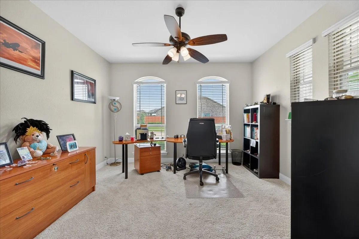Carpeted interior space featuring two arched windows, two rectangular windows, and a ceiling fan with integrated lighting
