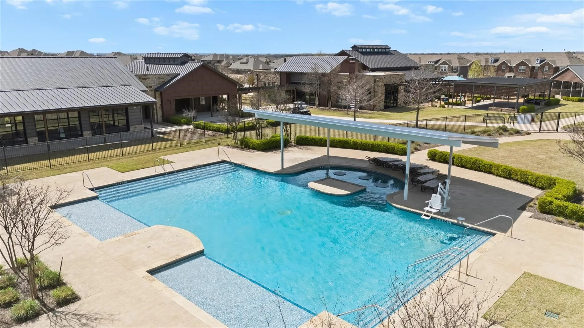 Community swimming pool with sun shelf, integrated steps, and surrounding lounge area