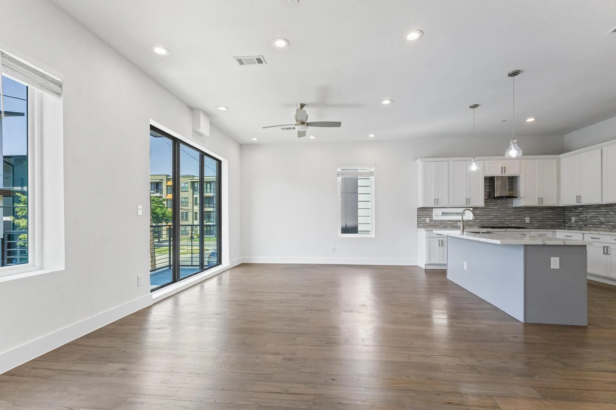 Open-concept living space with wood-finish flooring, recessed lighting, and a ceiling fan