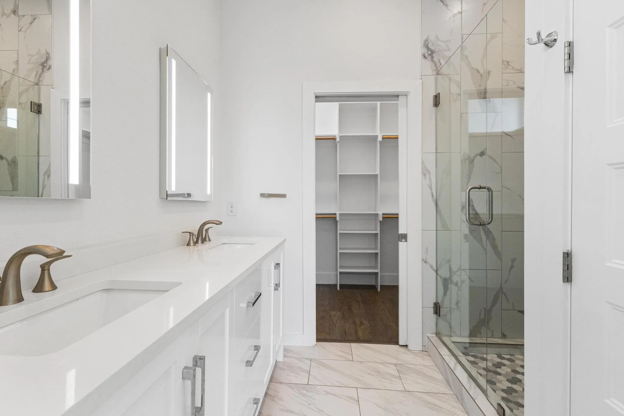 Dual vanity with integrated sinks, white cabinetry, and wall-mounted illuminated mirrors