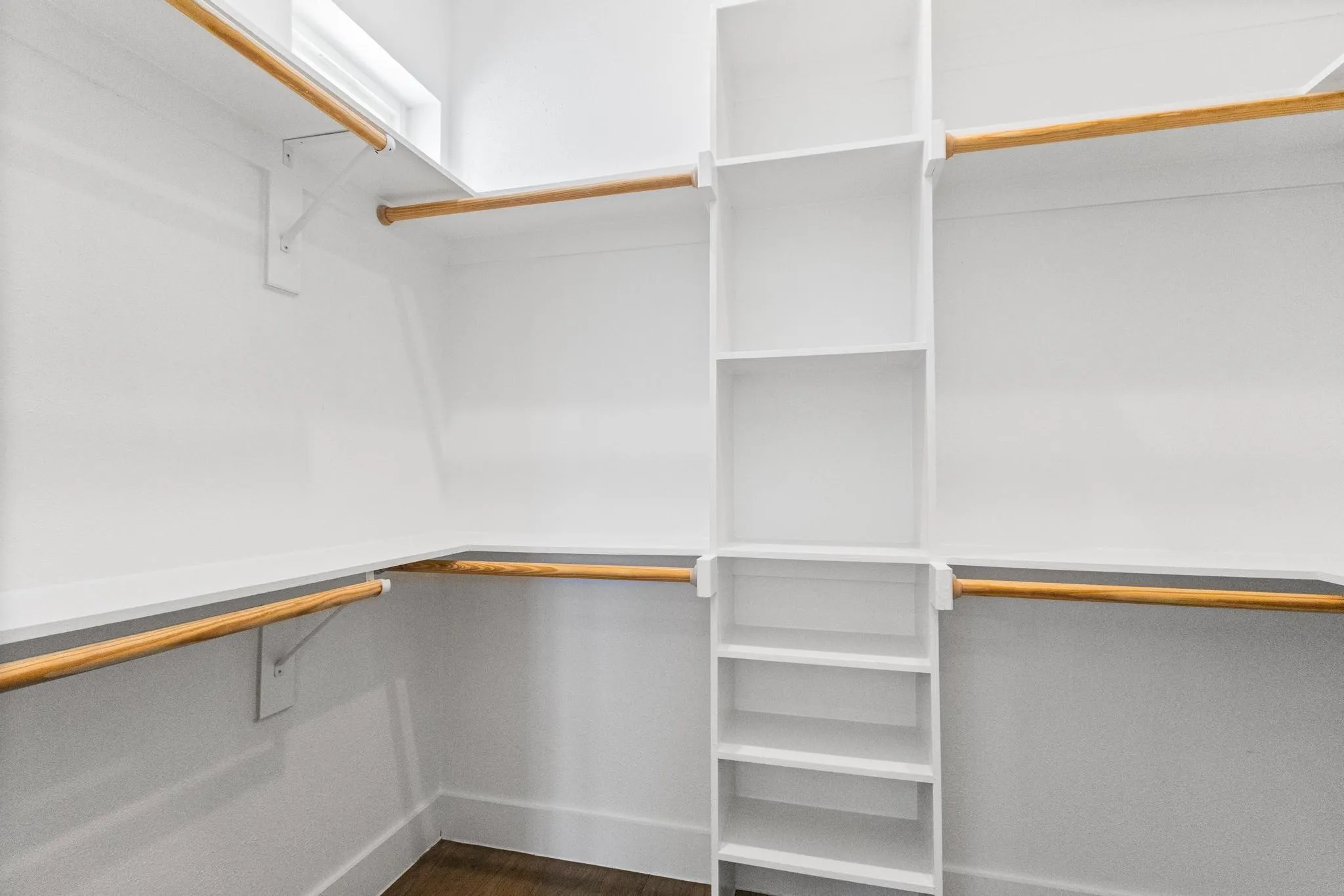 Built-in closet system with shelving, hanging rods, and wood-finish flooring